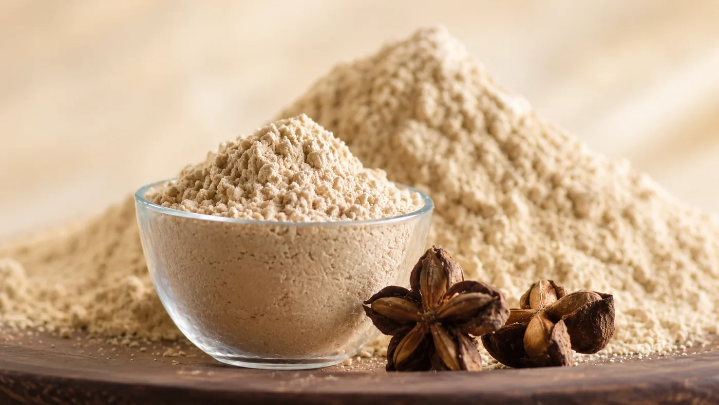 Sacha Inchi protein powder in a glass bowl beside sacha inchi seed pods